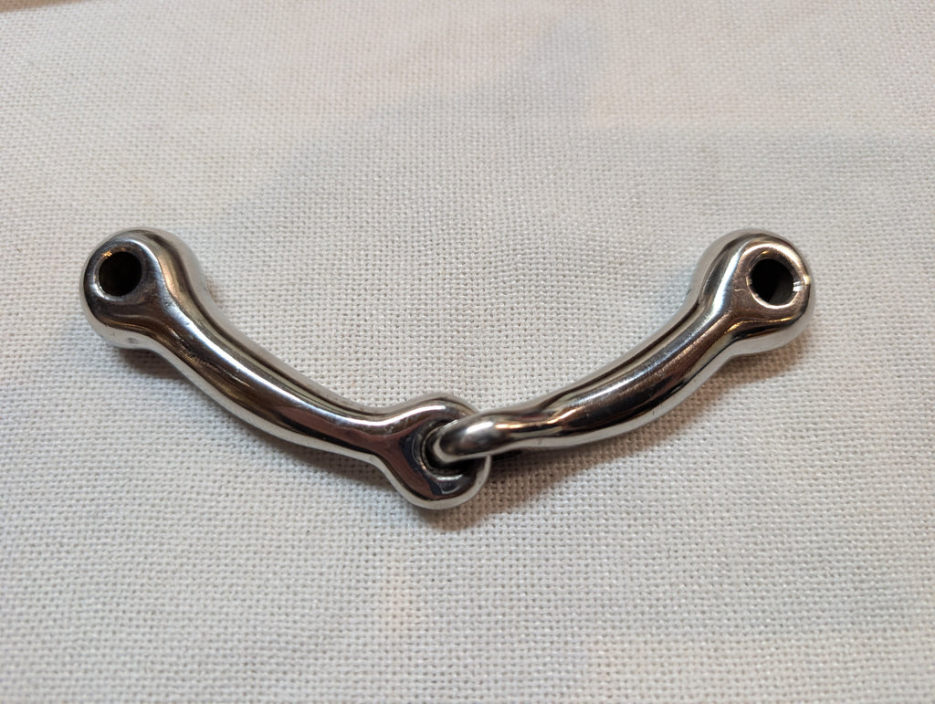 Metal snaffle bit on a light fabric background