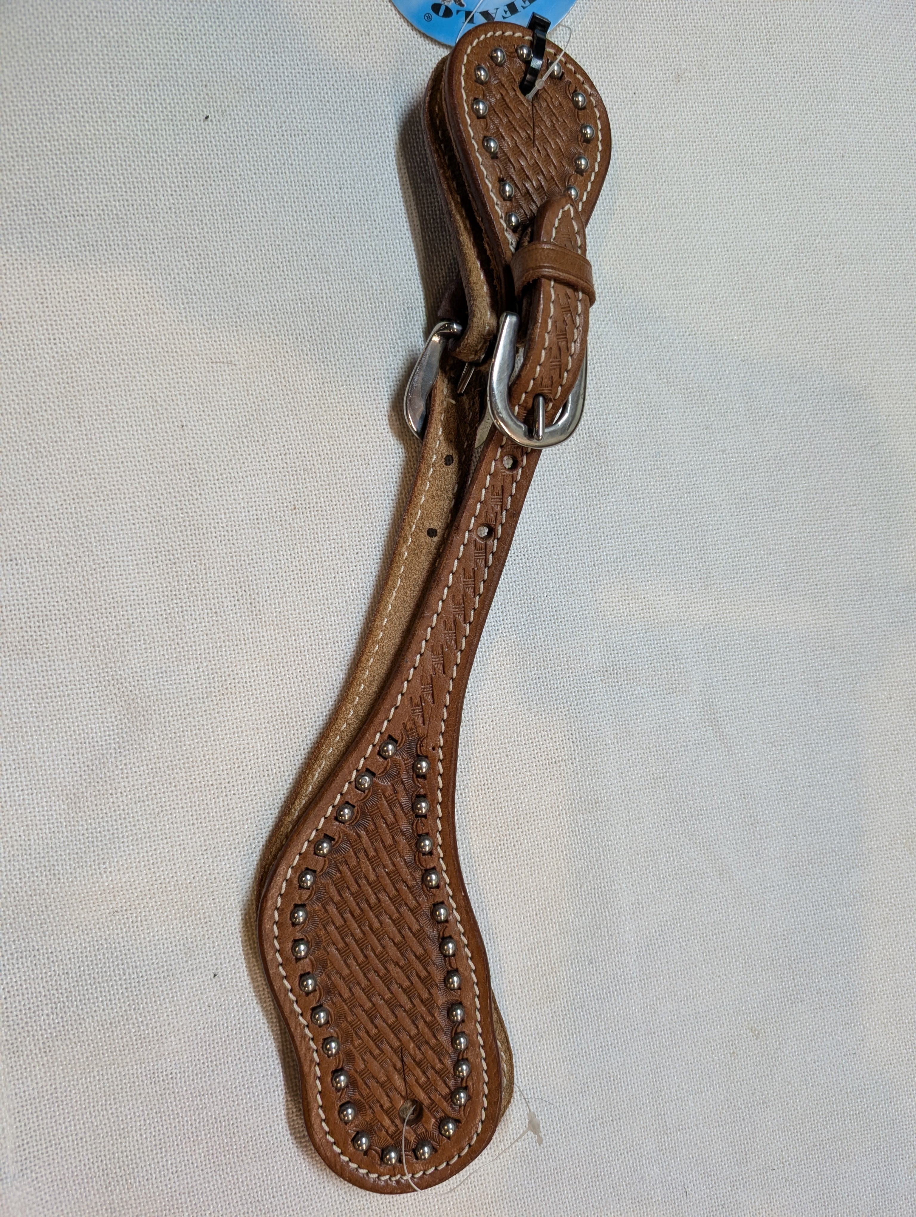 Brown leather spur with studs on a light gray background