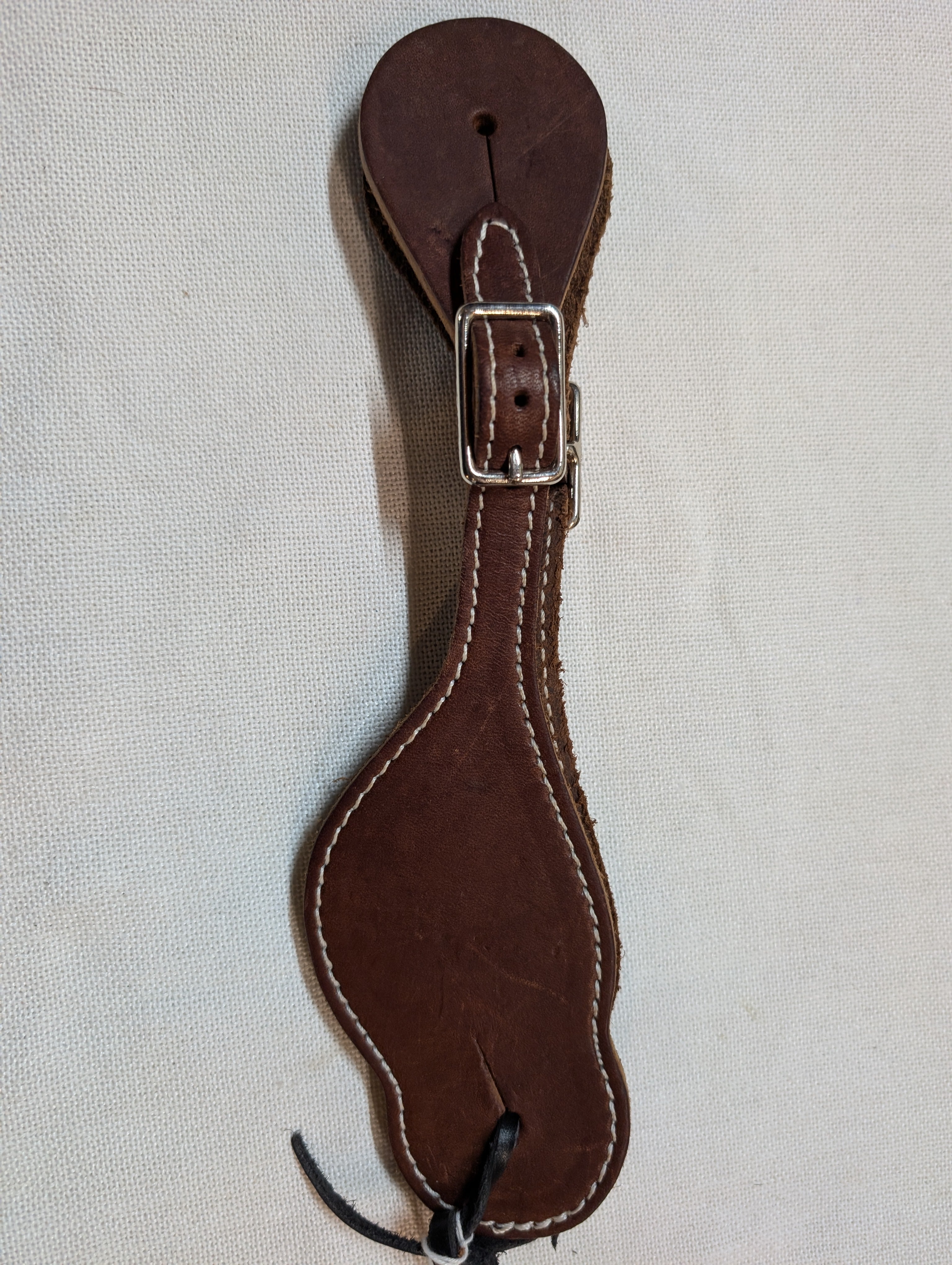 Brown leather strap with a buckle on a light gray background