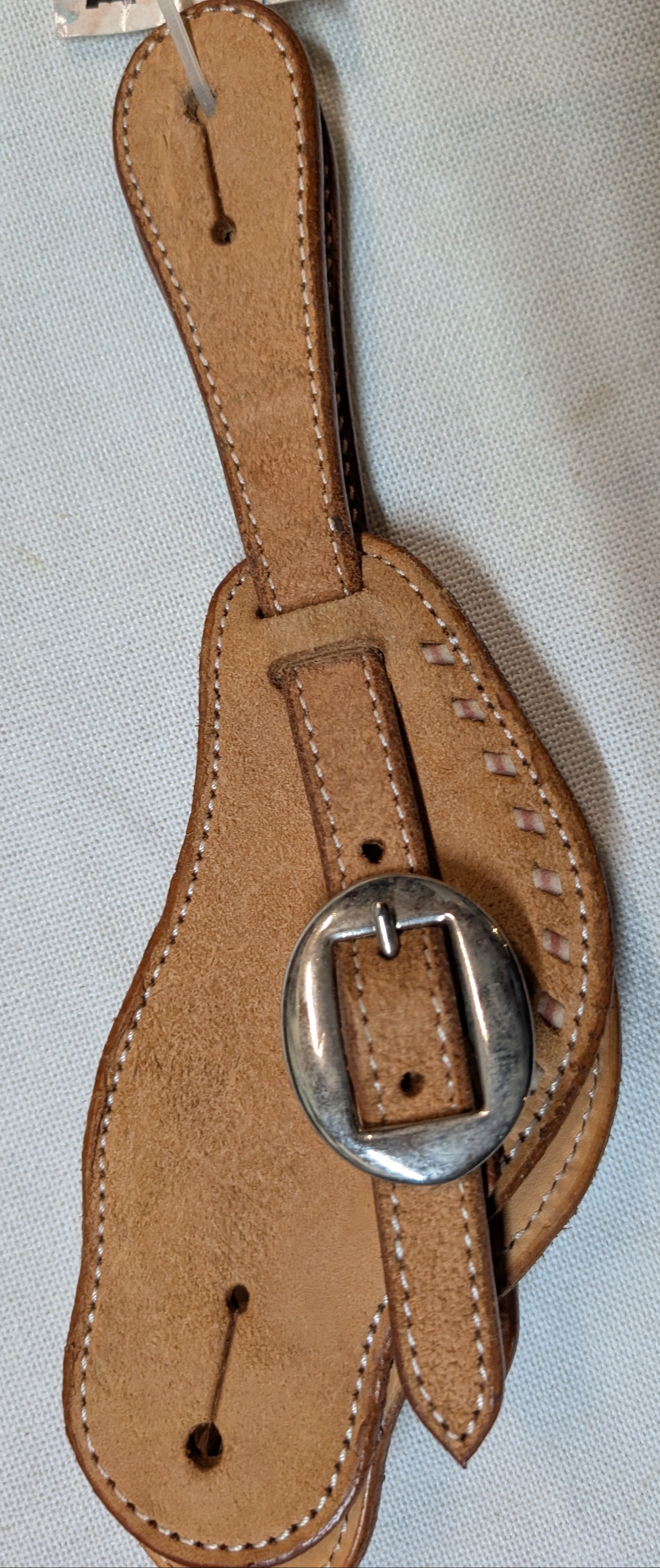 Brown leather strap with silver buckle on a light gray background