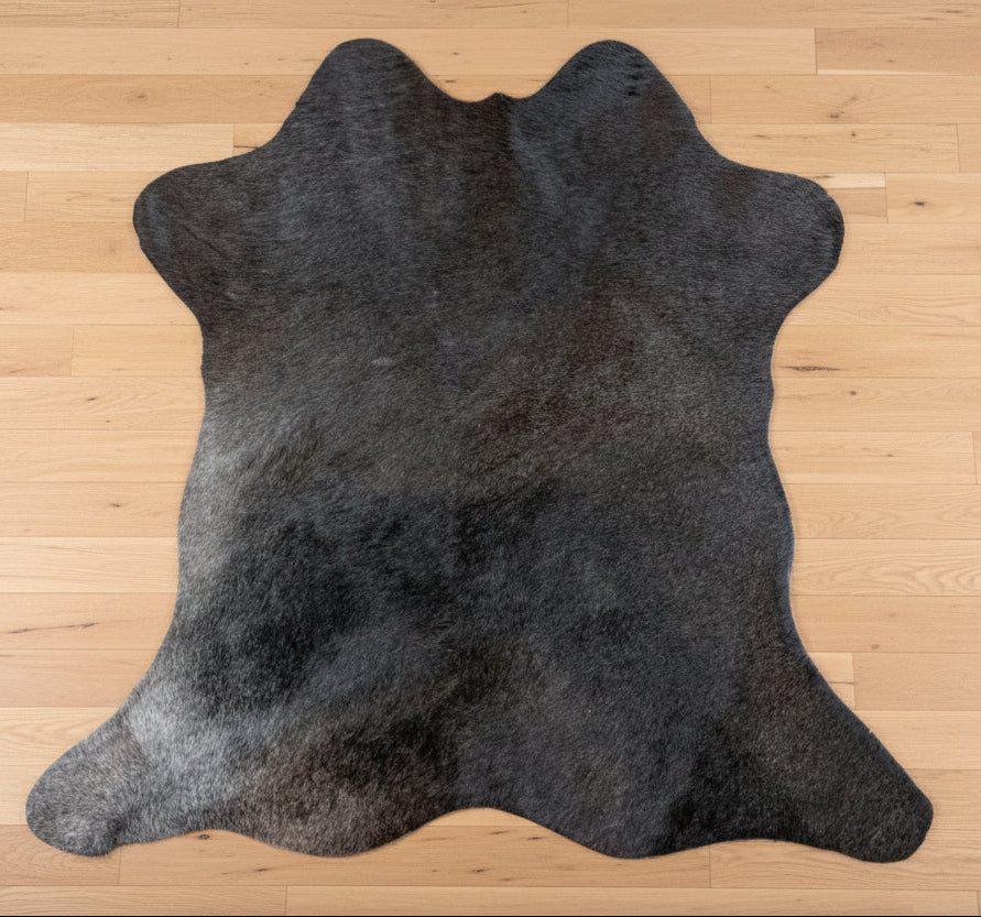 Black cowhide rug on a beige tiled floor