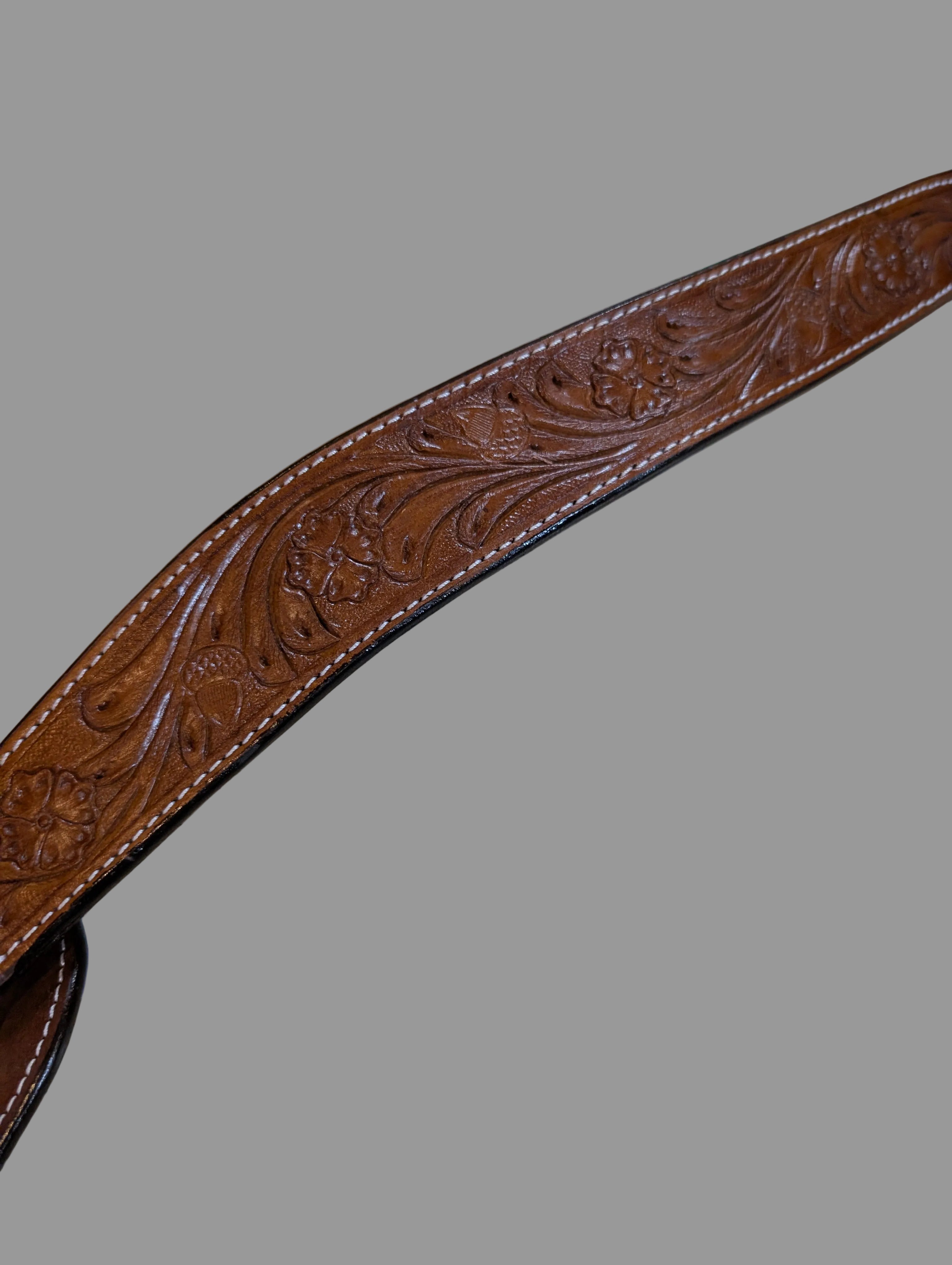 Brown leather belt with intricate embossing on a speckled surface