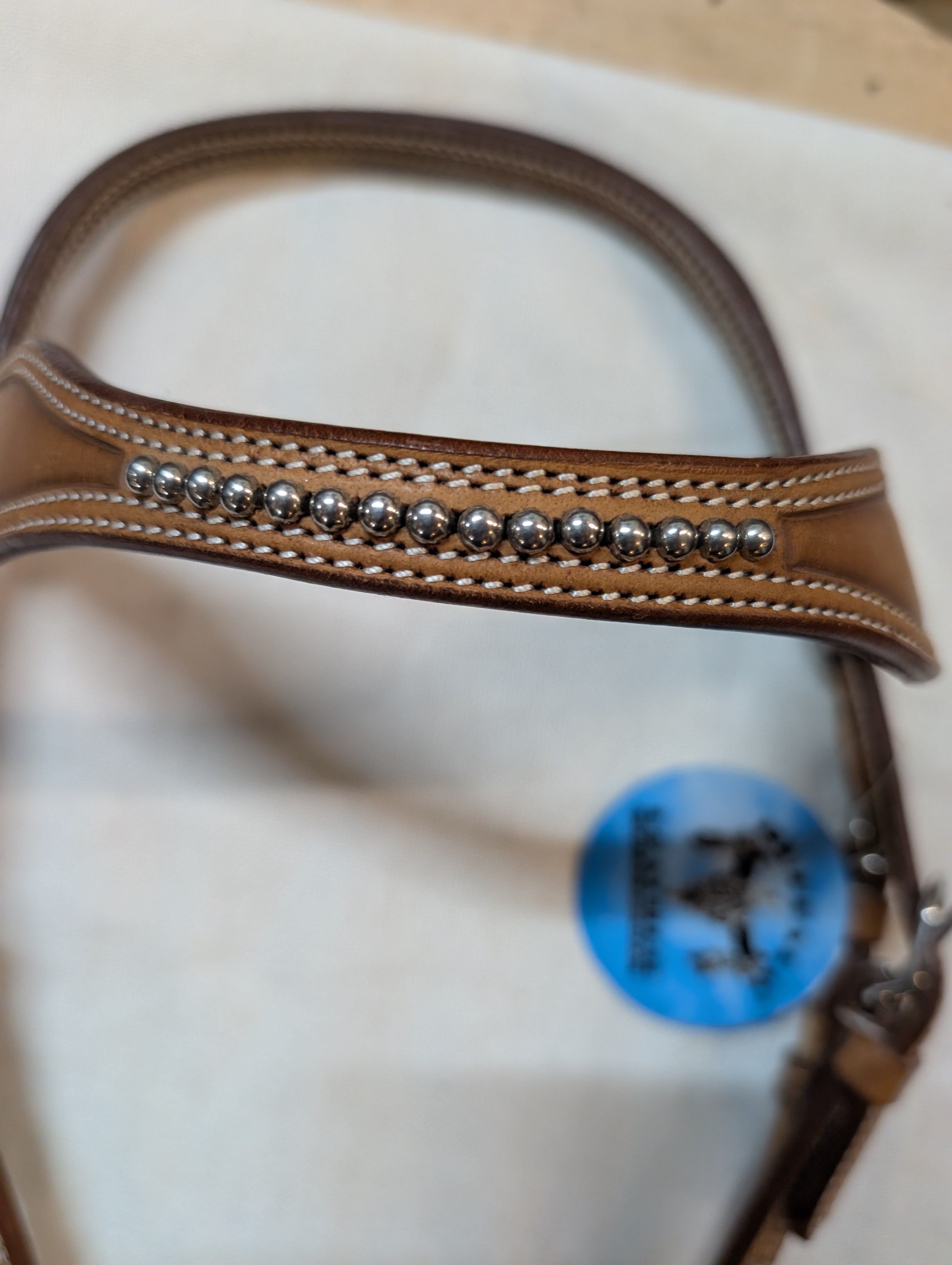Brown leather bridle with decorative studs on a white background