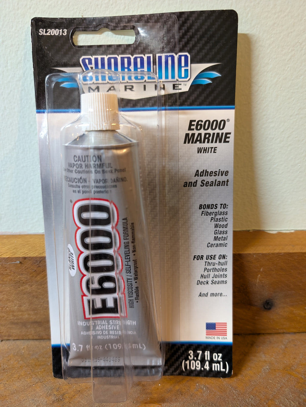 Shoreline Marine E6000 Marine adhesive tube packaging on a wooden surface