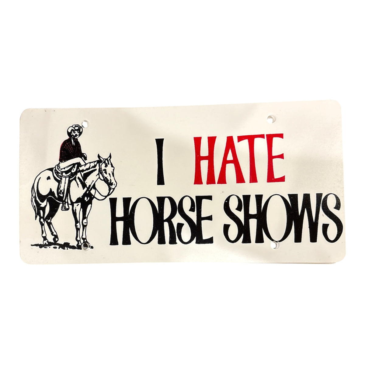 A plastic licence plate with a featuring a black illustration of a cowboy riding a horse and the text 'I HATE HORSE SHOWS' in black and red lettering.