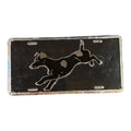 A rectangular black license plate featuring a raised silver silhouette of a leaping dog, shown against a plain white background.