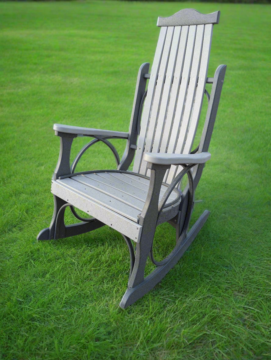 Gray rocking chair on a concrete surface with greenery in the background