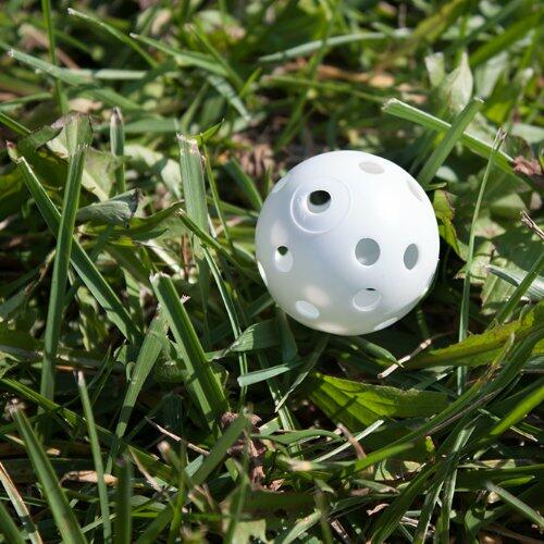 White plastic golf ball with holes on grass