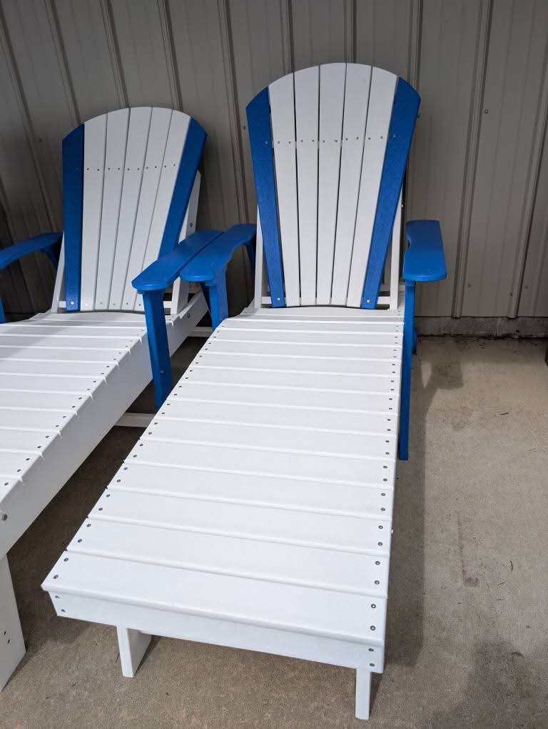 Two white lounge chairs with blue armrests and backrests on a concrete floor.
