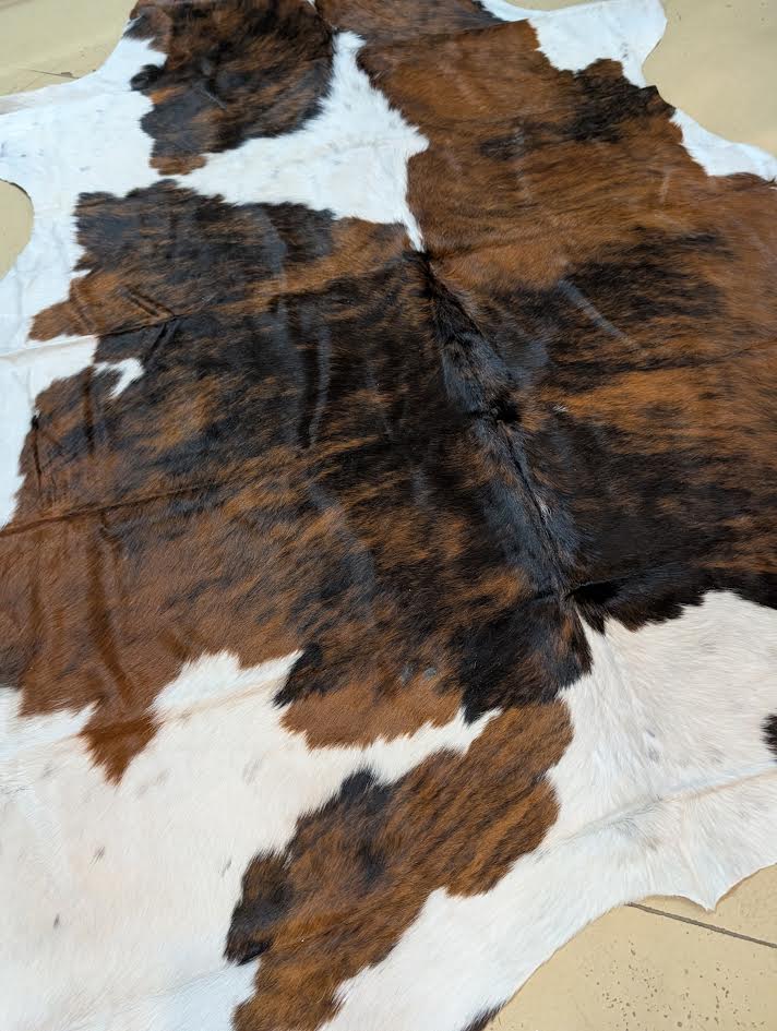 Brown and white cowhide rug on a beige surface