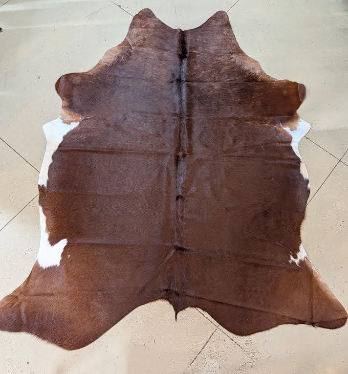 Red Herford cowhide rug on a tan floor