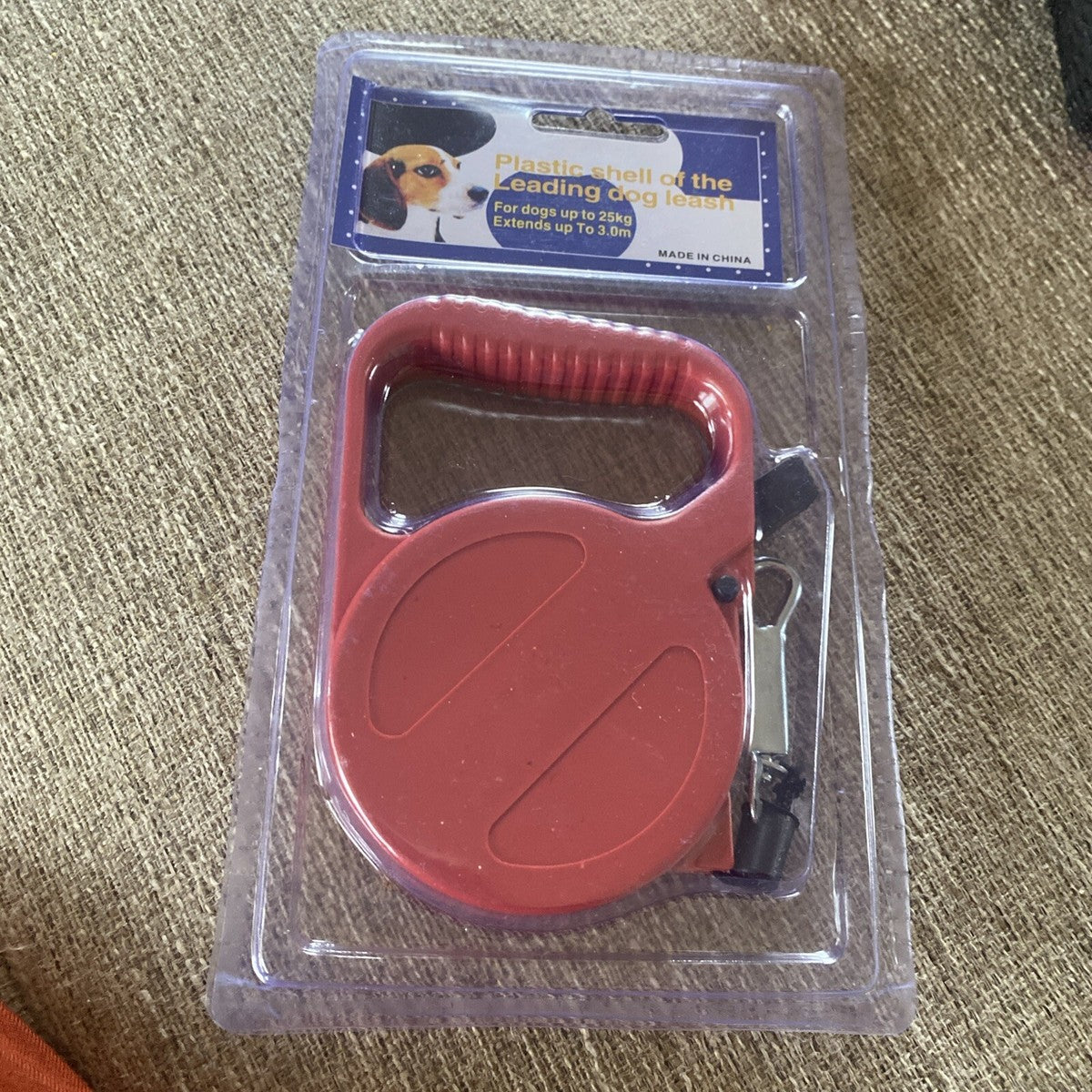 Small dog on a walk with a black retractable leash held by a person’s hand.