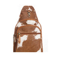 Brown and white cowhide patterned sling bag on a white background