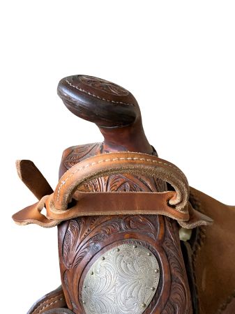 Close-up of a brown leather saddle with intricate designs on a white background