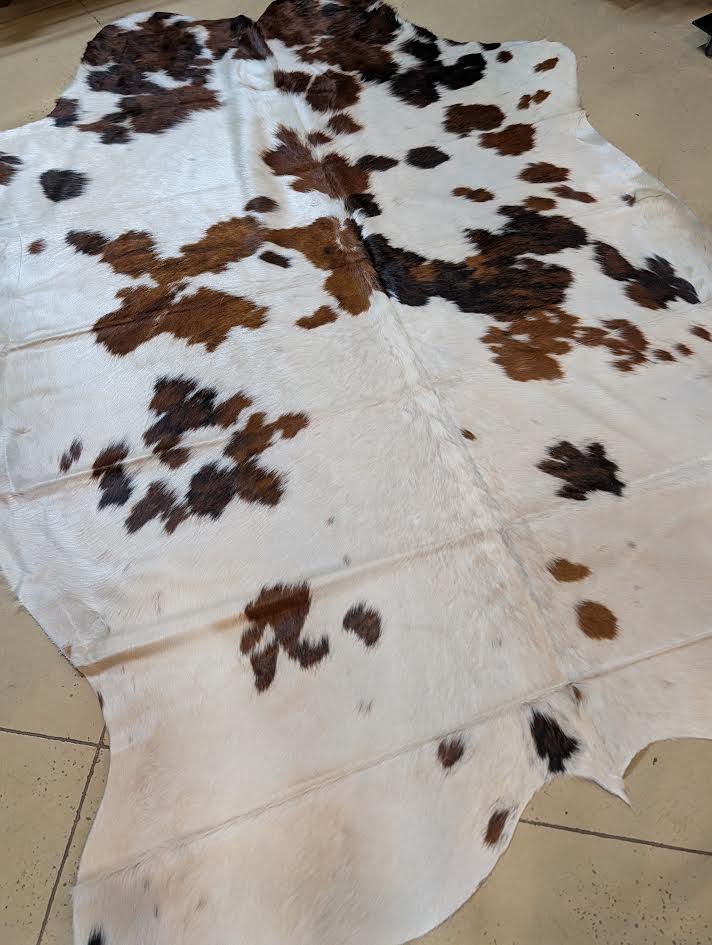 Cowhide rug with brown and black patches on a beige floor.