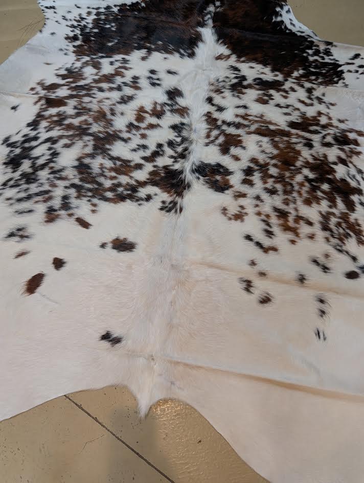 Cowhide rug with speckles on a tan floor.