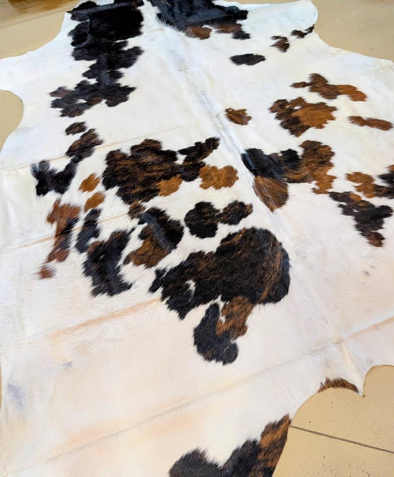 Cowhide rug with black, brown, and white pattern on a tiled floor.