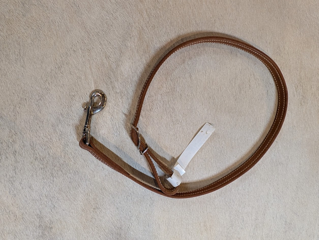 Brown leather tie down strap with a snap on a white surface