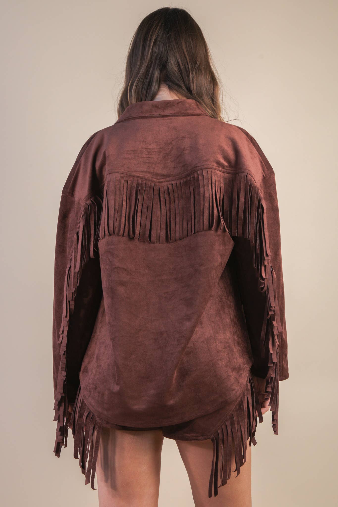 Brown suede fringe jacket worn by a person on a beige background