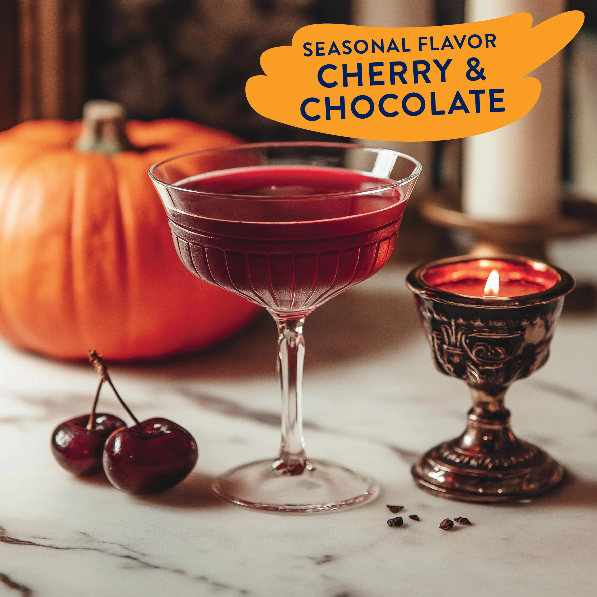 Red cocktail in a glass with cherries and a lit candle on a marble surface, labeled 'Seasonal Flavor Cherry & Chocolate'.