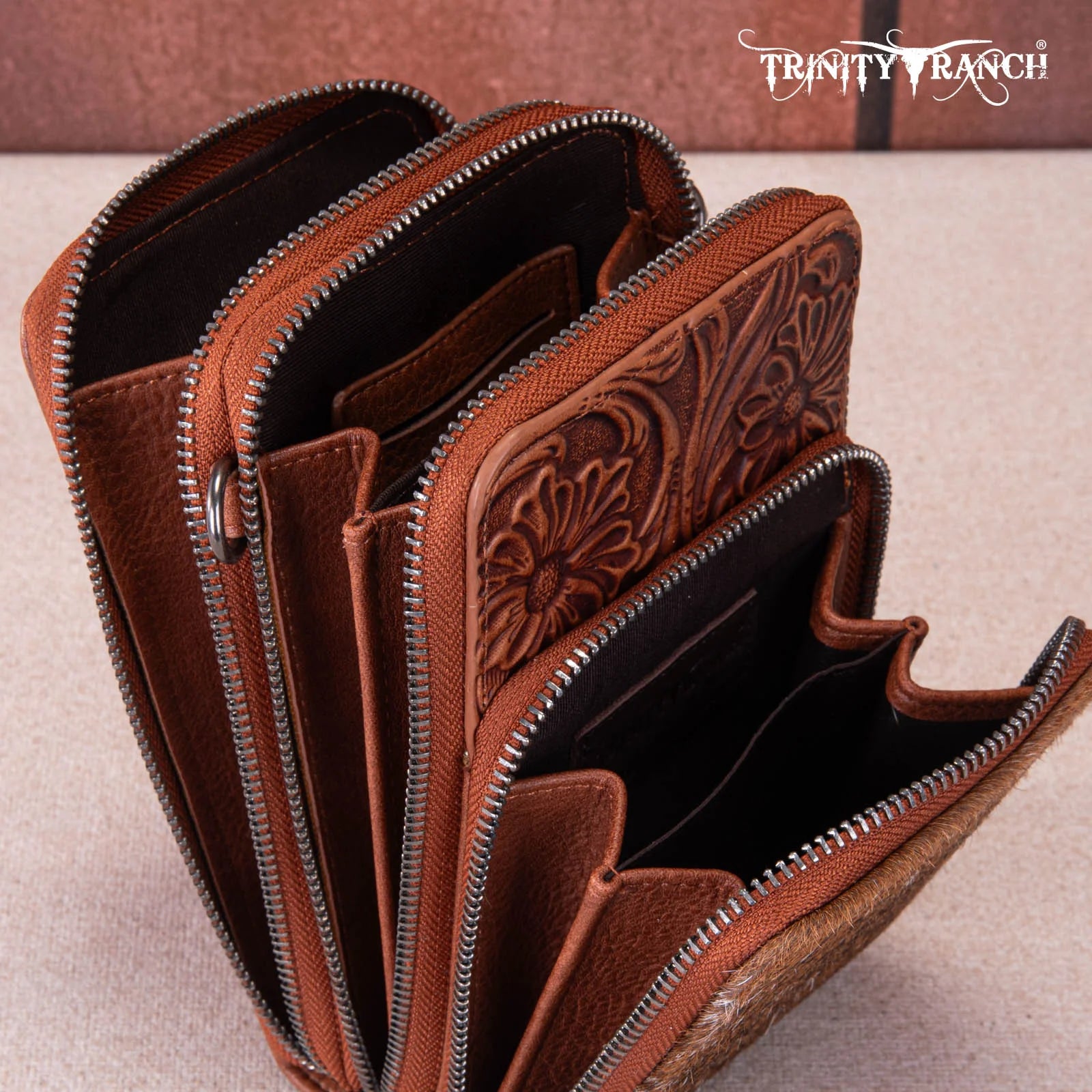 Brown leather wallet with intricate designs and zippers, featuring the Trinity Ranch brand.