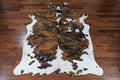 Brindle and white cowhide rug on a brown wood floor