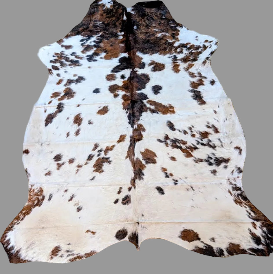 Tri-color cowhide rug with a gray background.