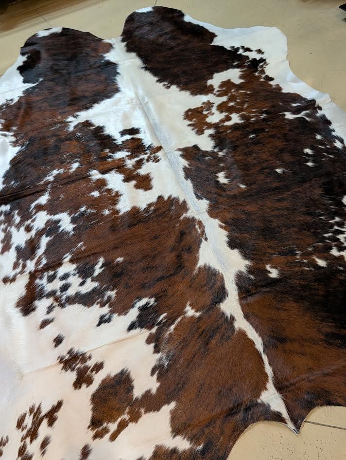 Brown and white cowhide rug on a wooden floor