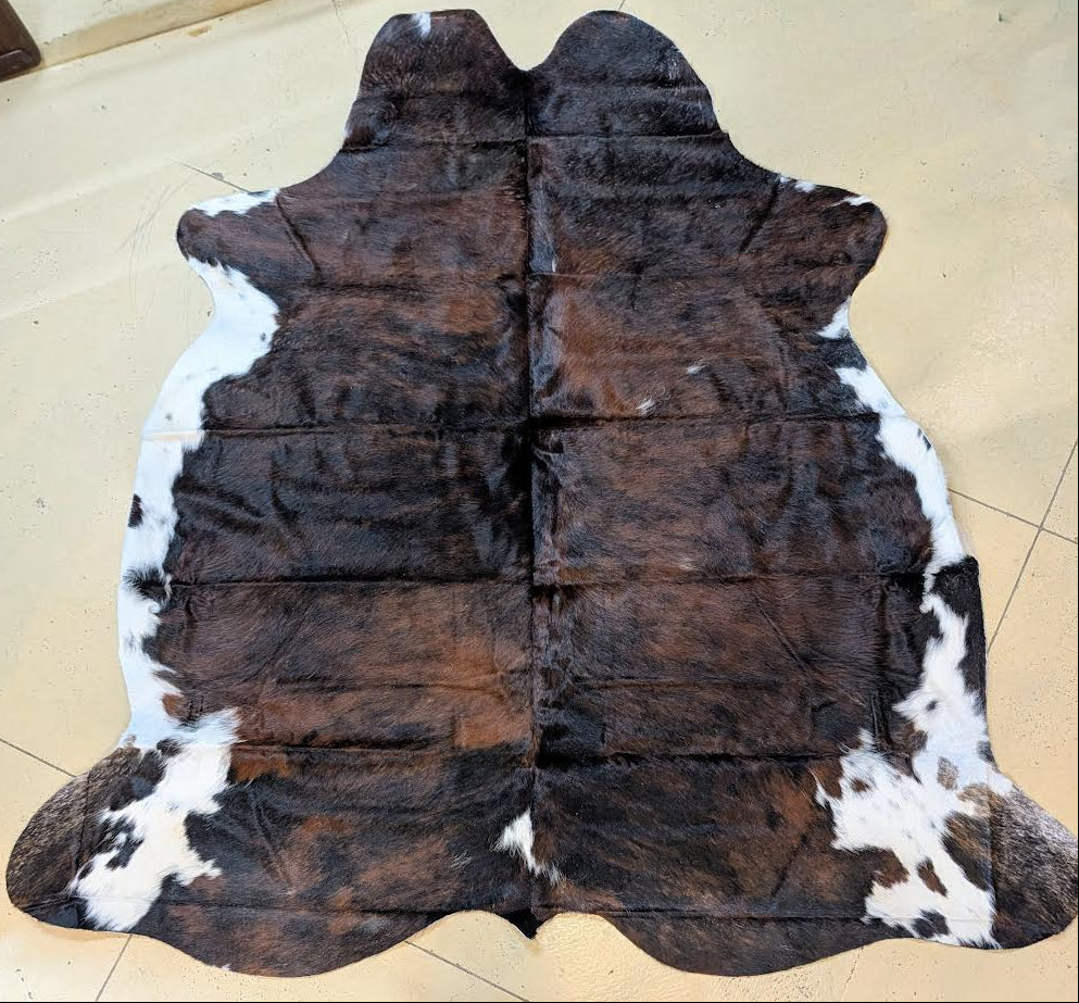 Brown and white cowhide rug on a tiled floor