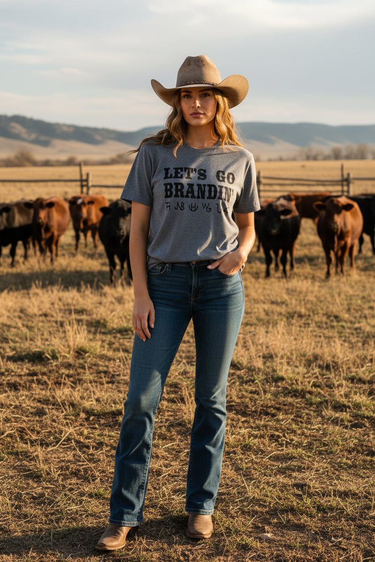 Lady wearing a graphic short sleeve tee shirt with cows in the background. 