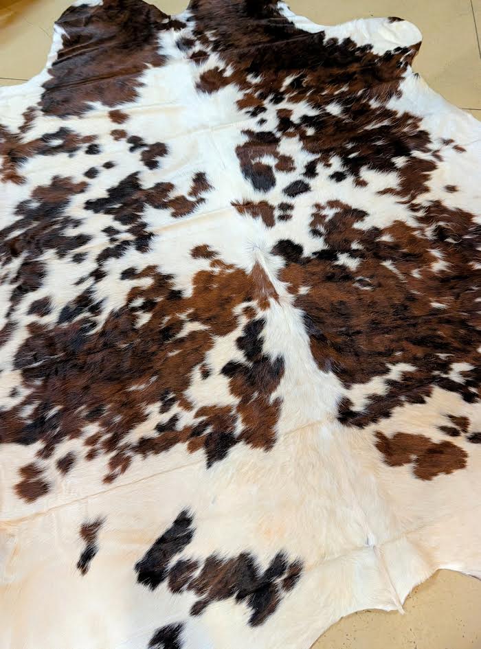 Brown and white cowhide rug on a beige surface