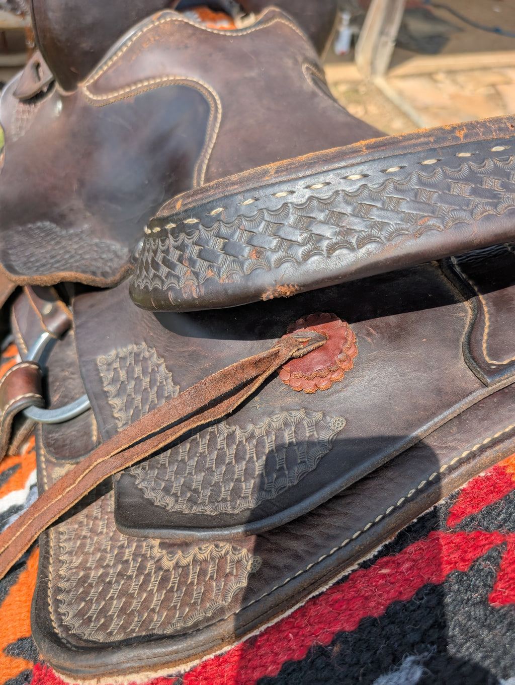 Close-up of a leather saddle with intricate patterns on a colorful fabric background