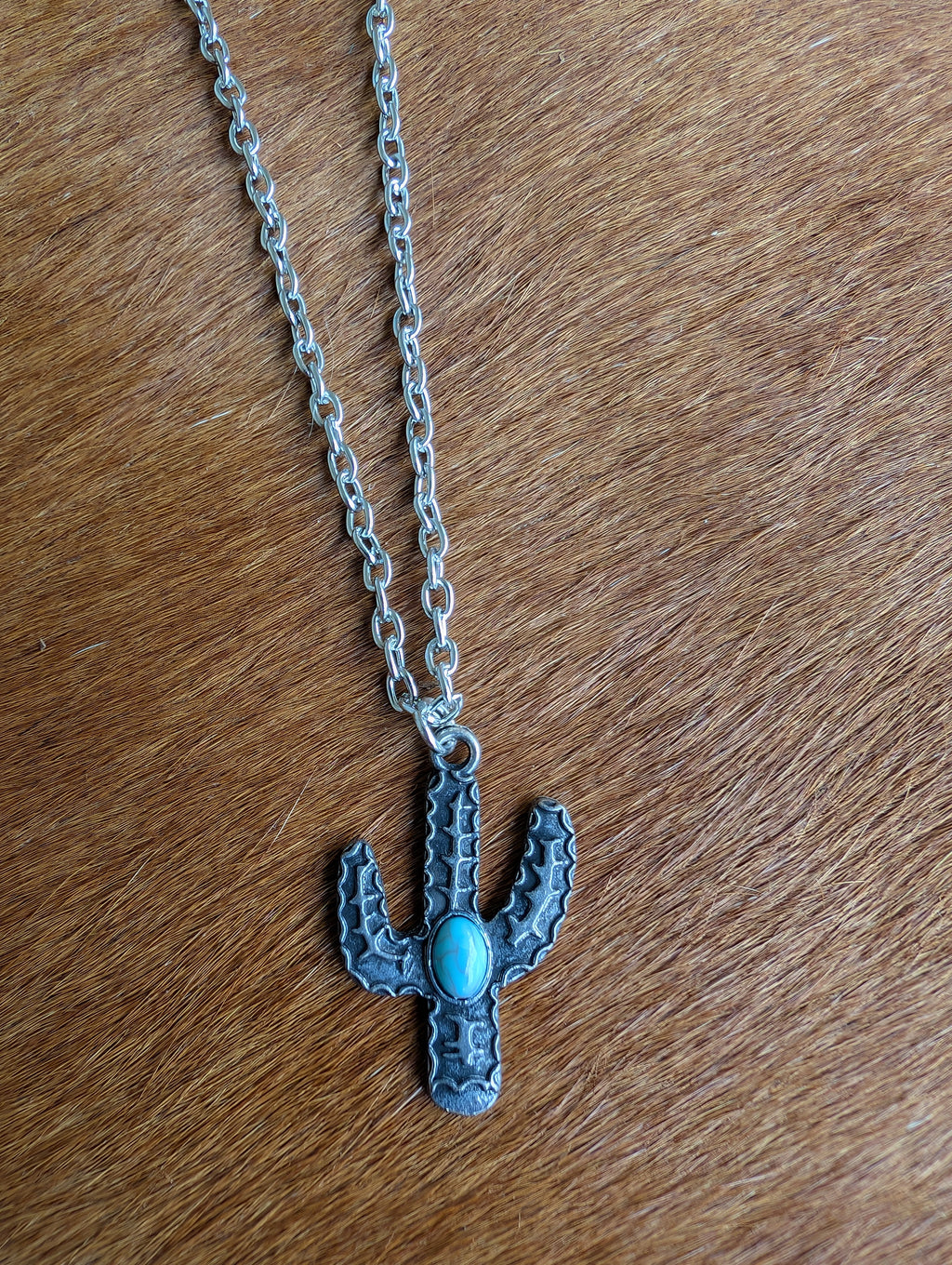 Western-style cactus pendant with carved details and turquoise accents