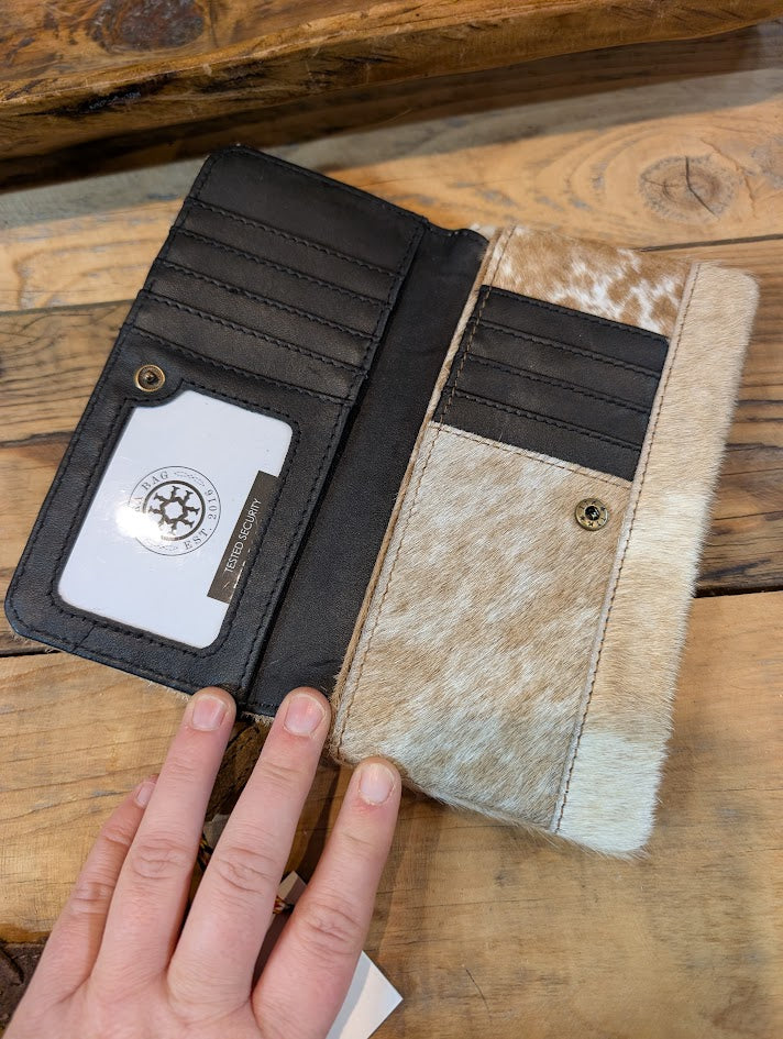 Hand holding a wallet with a visible brand logo on a wooden surface