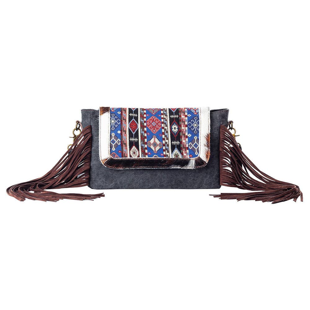 Canvas & Cowhide shoulder bag with fringe with a white background.
