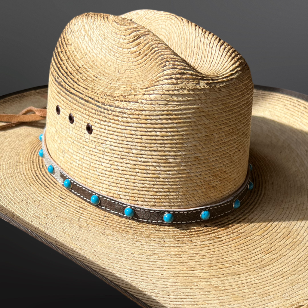 Straw hat with a western hair-on hat band featuring blue beads on a dark background