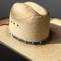 Straw hat with a western hair-on hat band featuring blue beads on a dark background