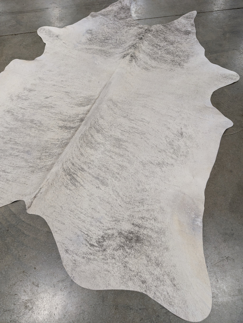 White & Grey brindle Cowhide Rug laying on floor