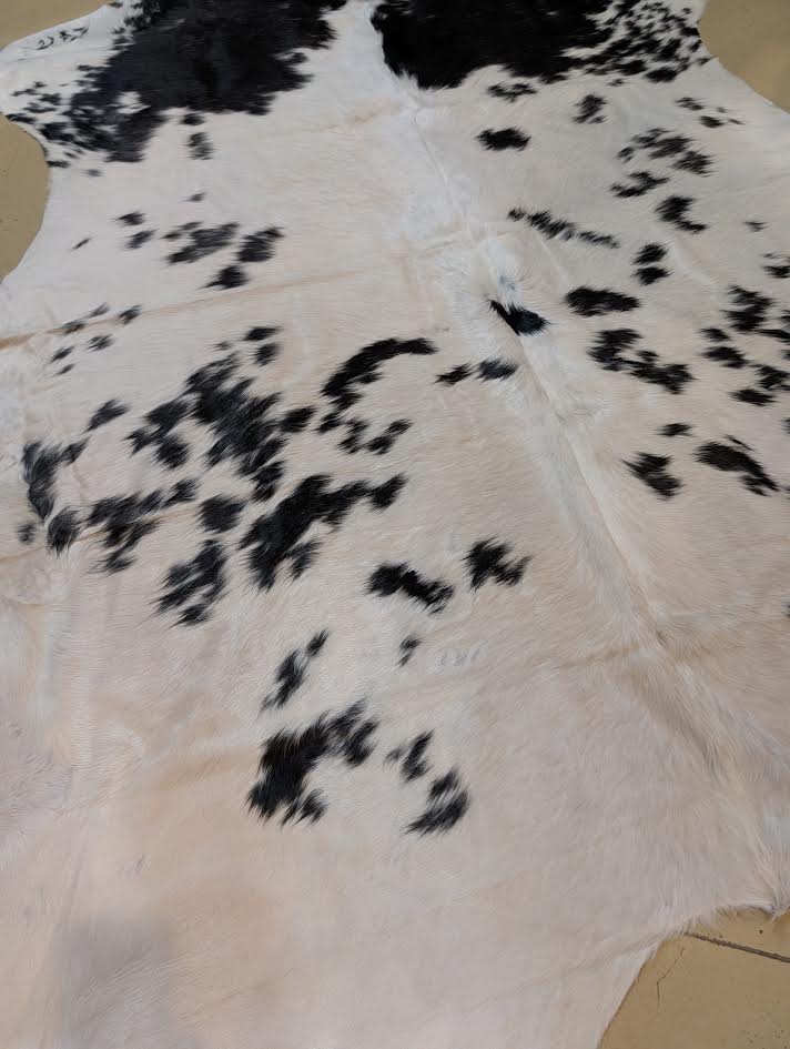 Cowhide rug with black and white pattern on a beige surface
