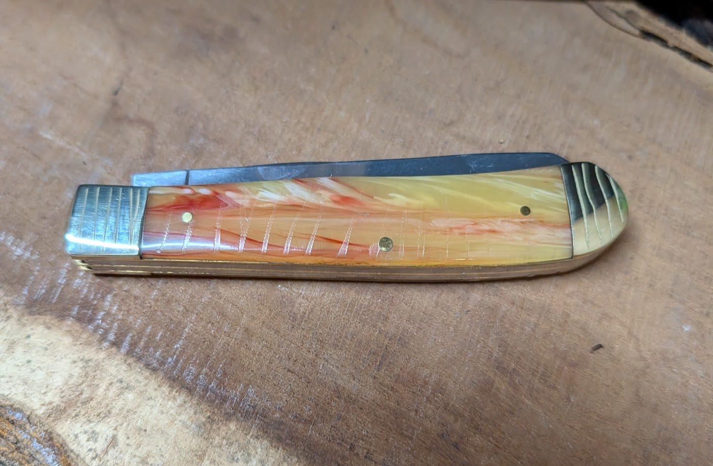 Folding knife with a colorful handle on a wooden surface