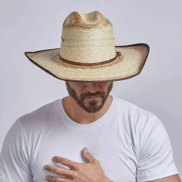 Man wearing a straw cowboy hat on a plain background