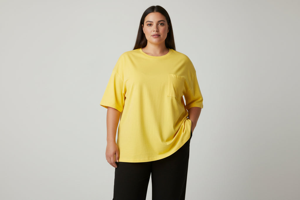Yellow Plus size top on a lady with black pants and a white background.