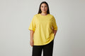 Yellow Plus size top on a lady with black pants and a white background.