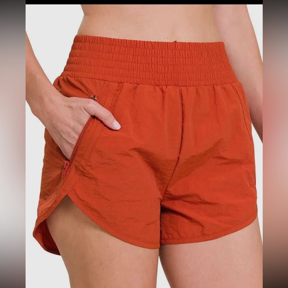 Orange shorts worn by a person on a plain background