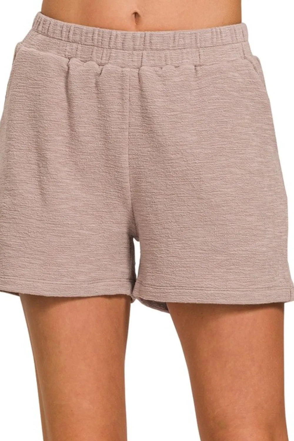 Beige shorts worn by a person on a white background