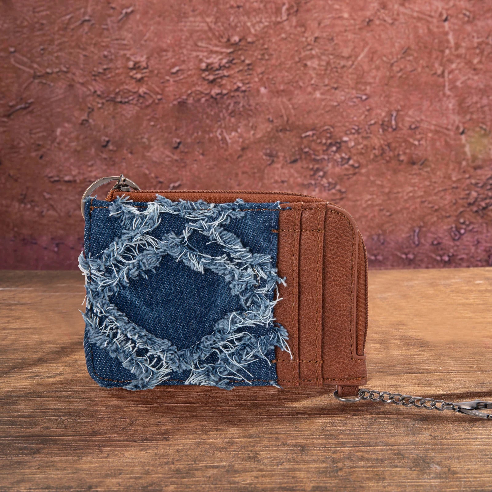 Blue Jean denim and brown faux leather Wrangler by Montana West mini zip card holder on a rustic wooden background.