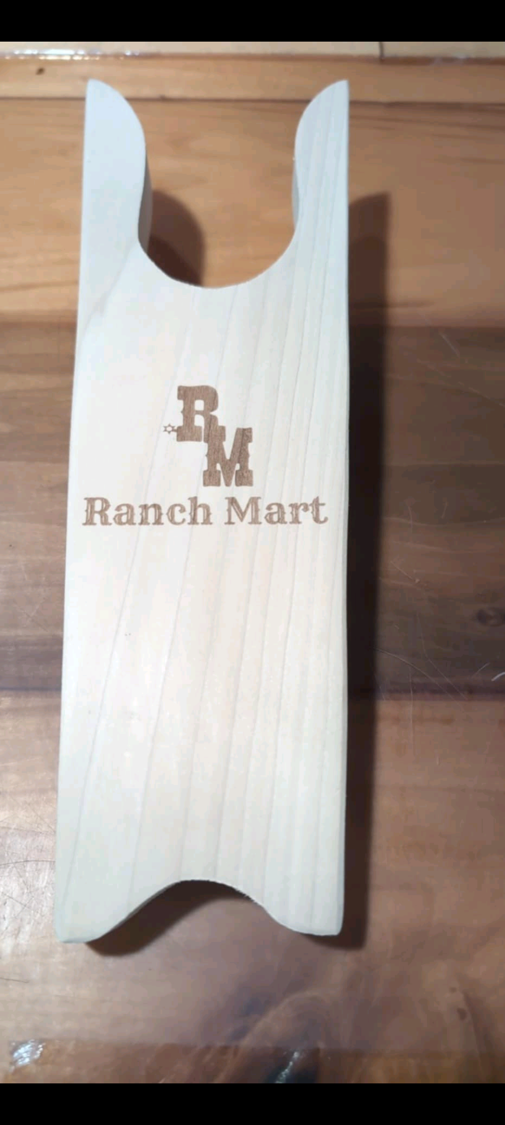 Wooden boot jack with 'Ranch Mart' branding on a wooden surface