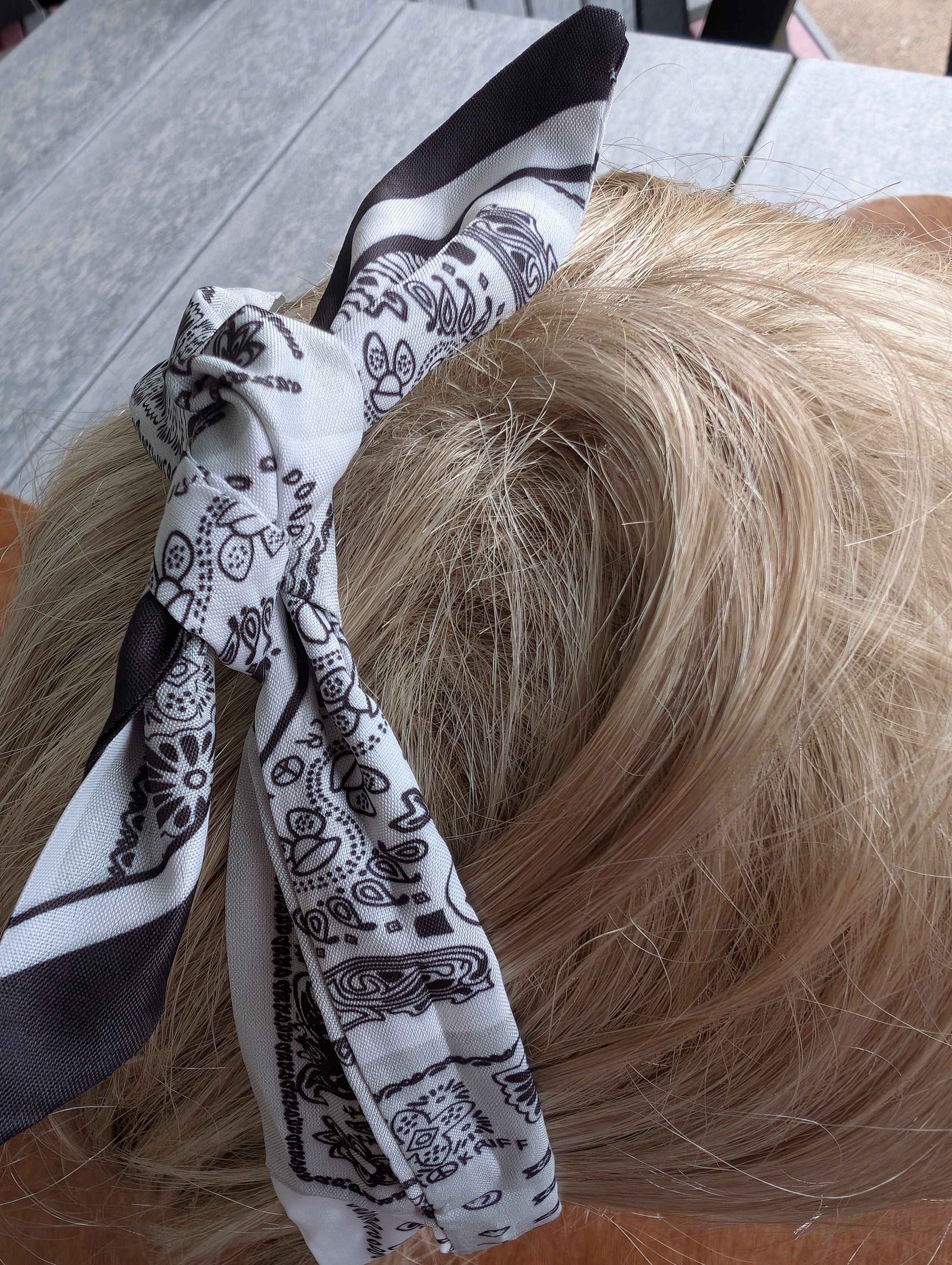 "Bandana-inspired hair scarf shown tied in a bow with soft fabric texture"