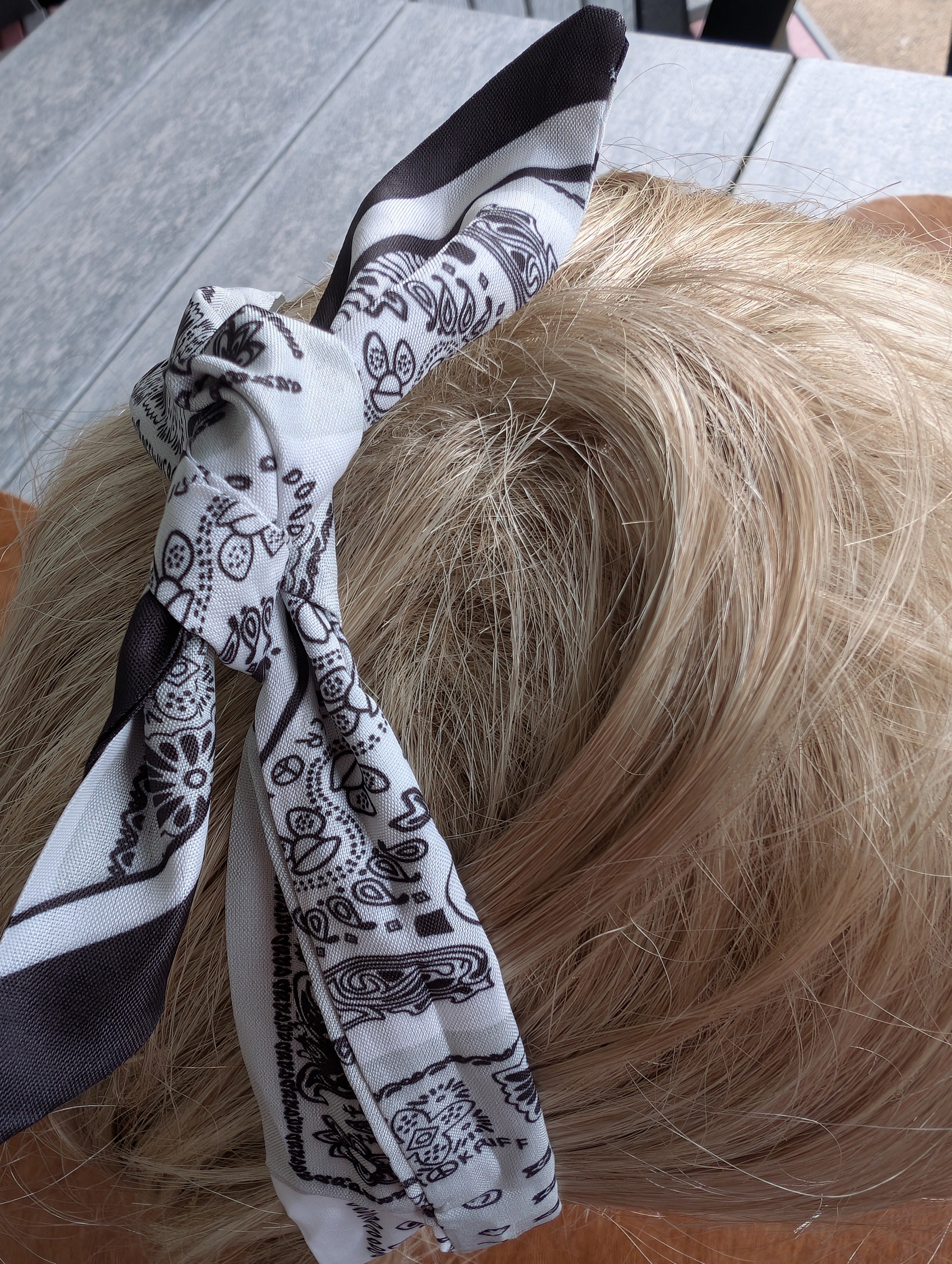 "Bandana-inspired hair scarf shown tied in a bow with soft fabric texture"
