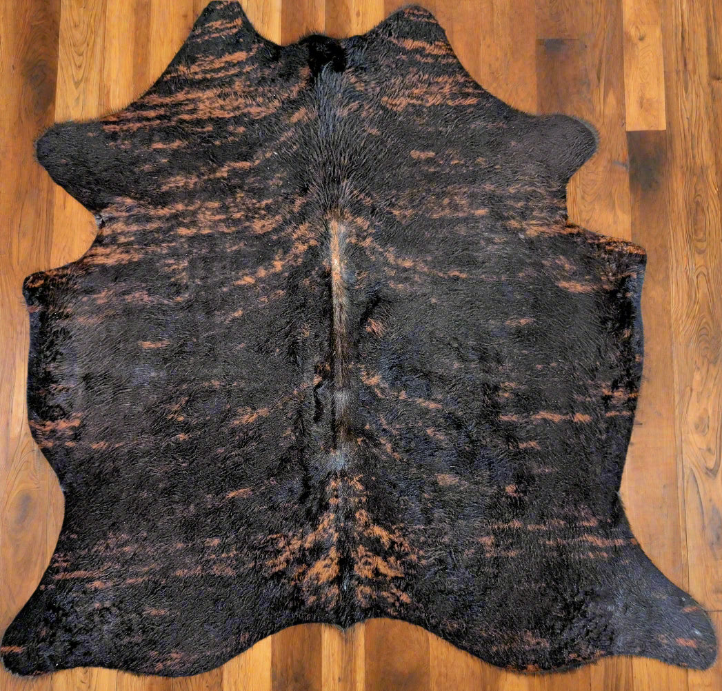 Individually named Bungle a dark brindle cowhide rug laid out on a wooden floor.